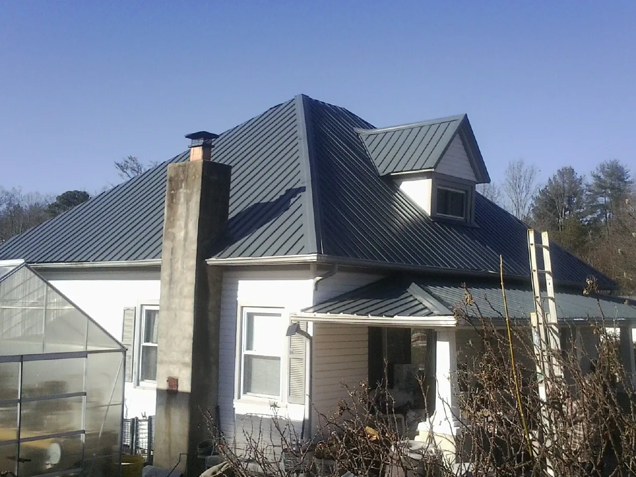 Dark blue standing seam metal roof on a white farmhouse with dormer — Slate & Tile Roof Repair by Roofing Brothers in Newmanstown