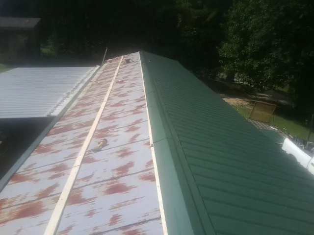 Old rusted panels beside newly installed green metal roofing — Wind Damage Roof Repair by Roofing Brothers in Newmanstown