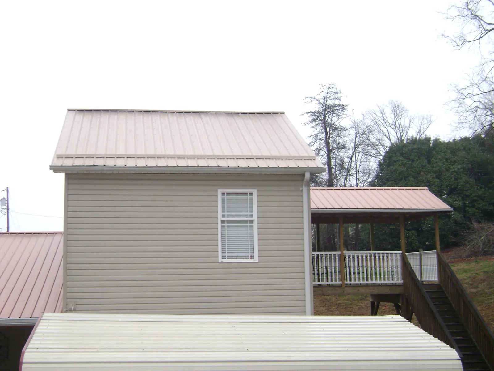 Tan metal roofs on a two story addition and attached porch, from a Roof Replacement job in Newmanstown