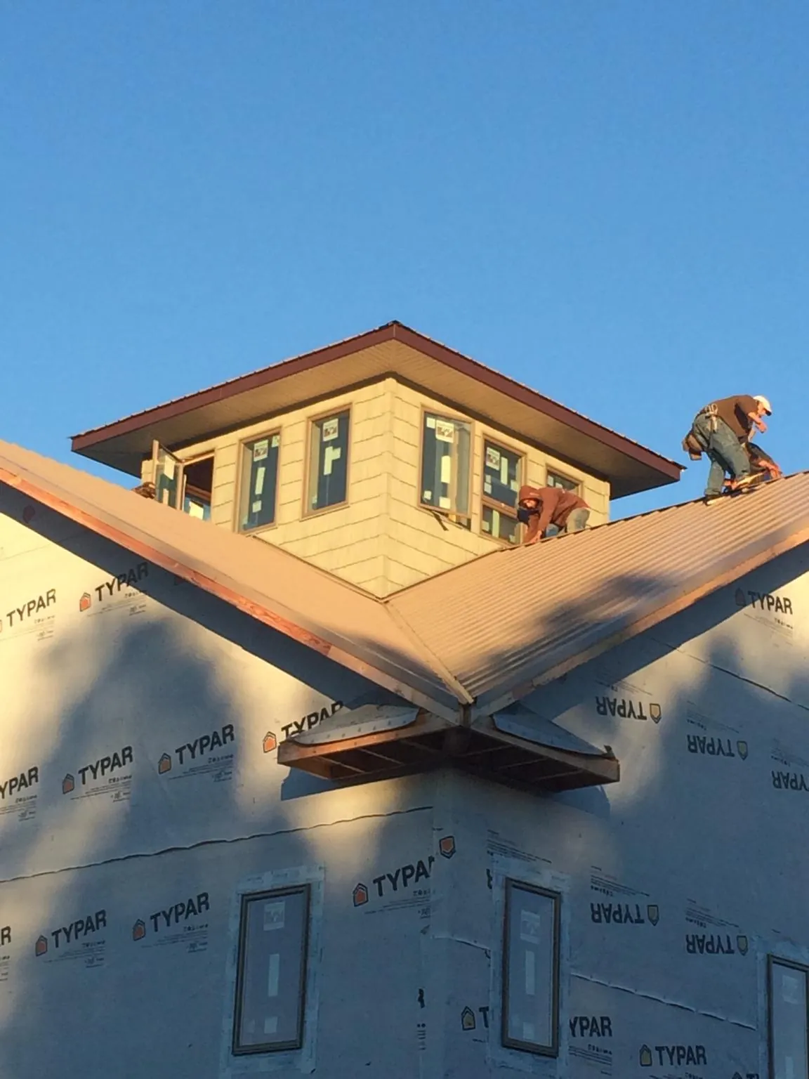 Roofers working around a rooftop cupola on a new metal roof at sunset — Roof Waterproofing in Newmanstown by Roofing Brothers
